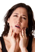 Woman with pain in jaw, holding the sides of her face