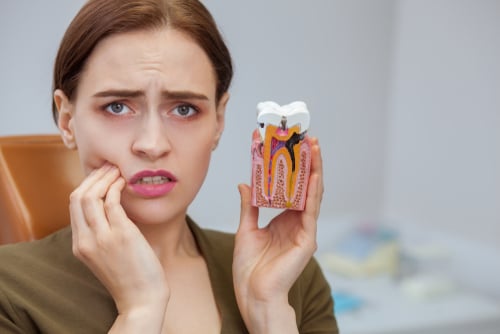 Woman in pain holding a model tooth